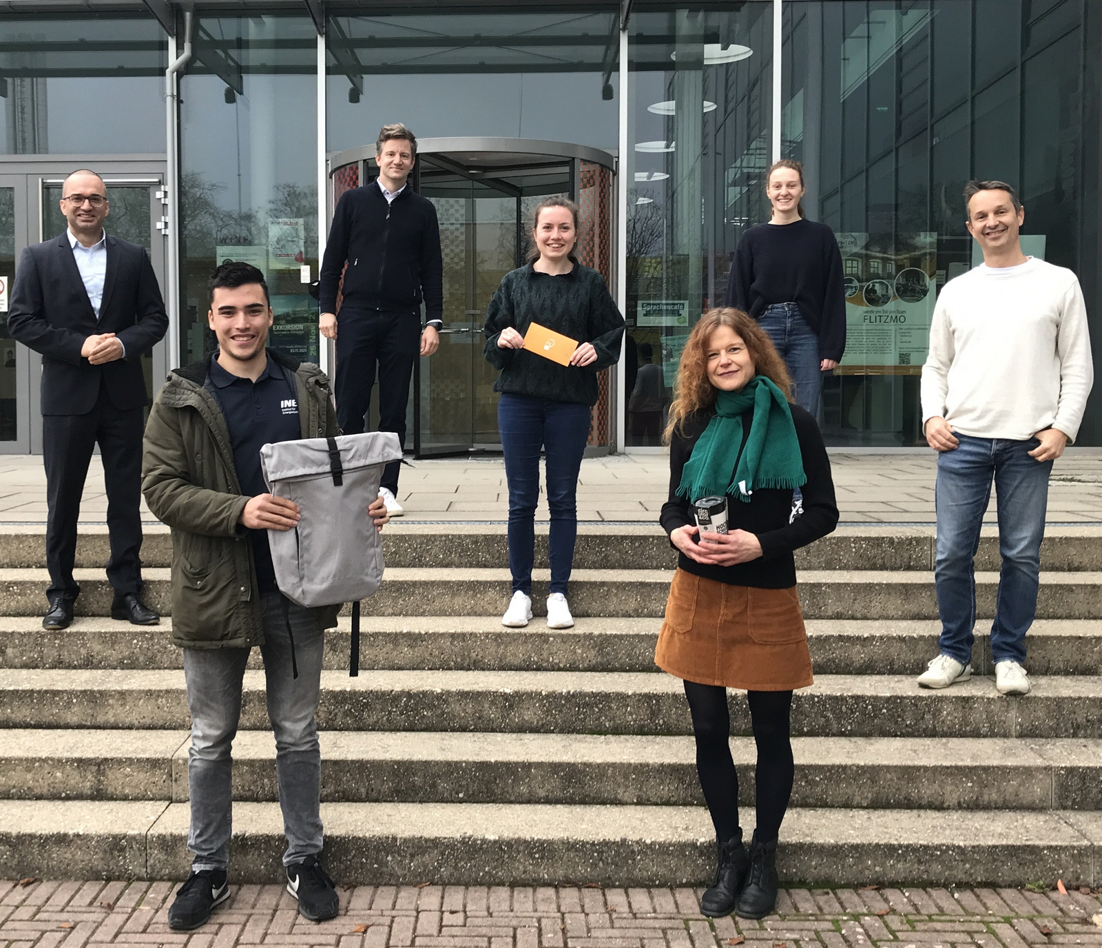 Kanzler Bülent Tarkan, Gewinner René Behmann, der stellvertretende Nachhaltigkeitsbeauftragte Niklas Hartmann, die Zweit- und Drittplatzierten Kathrin Grusa und Simone Schede, Jana Gebhardt von der AG Nachhaltigkeit und der Nachhaltigkeitsbeauftragte Daniel Kray stehen vor dem D-Gebäude.